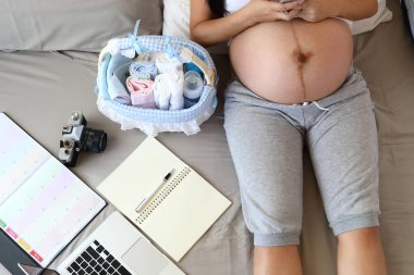 Yeni doğan anne annelik hazırlıkları bebek sevgisi, bebek bezi, sepetteki süt şişesi, dizüstü bilgisayar, defter çizelgesi...