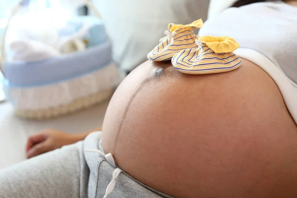 Roztomilý malý ponožka dát na matka bříško těhotná čeká na dítě novorozence — Stock fotografie