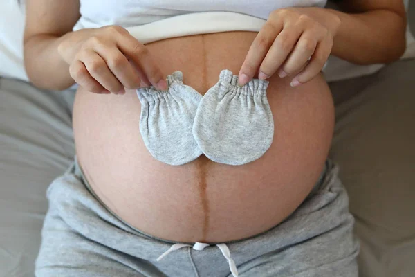 Schattig klein handschoen op moeder buik zwanger wachten voor baby pasgeboren — Stockfoto