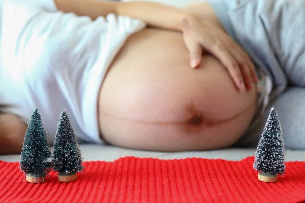 Kleiner Weihnachtsbaum auf rotem Garn mit schwangerem Hintergrund — Stockfoto