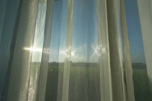阳光透过窗上的白色窗帘照射在窗户上 — 图库照片