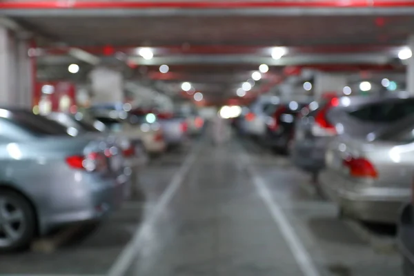 Subterrâneo do parque de estacionamento no edifício de negócios, imagem de fundo borrão — Fotografia de Stock