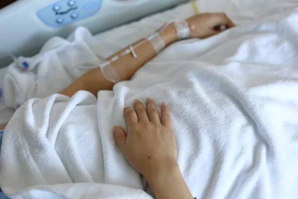 Женщина пациент отдыхает на кровати, рука с внутривенным вливанием физраствора внутривенно инъекционное лекарство для лечения заболеваний в больнице — стоковое фото