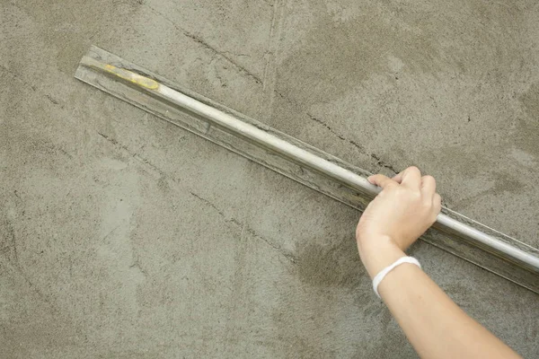 builder using trowel smoothing plaster on construction wall