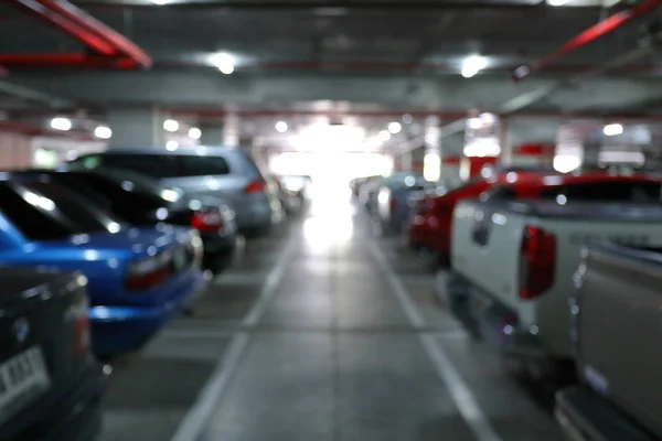 Subterrâneo do parque de estacionamento no edifício de negócios, imagem de fundo borrão — Fotografia de Stock