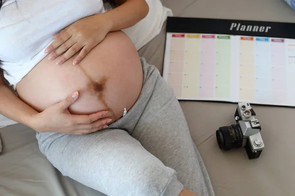 Moeder zwanger moederschap hand houden omarmen buik, mam met behulp van planner schema — Stockfoto