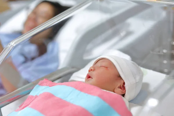 Pequeno bebê bonito dormindo perto da cama mãe após o parto recém-nascido no hospital — Fotografia de Stock