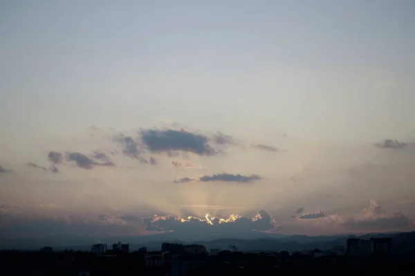 Světelné paprsky slunce na obloze nad městem — Stock fotografie