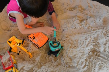 Çocuk kum parkında inşaat oyuncağı oynuyor.