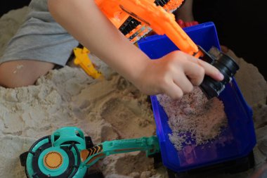 Çocuk kum parkında inşaat oyuncağı oynuyor.