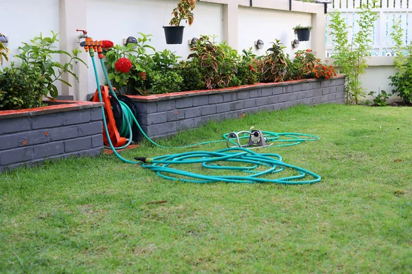 Watering hose equipment in green grass of backyard — Stock Photo, Image