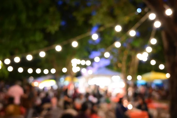 Lidé dav v noci party festival venkovní zahrady se žárovkou závěsné dekorace — Stock fotografie