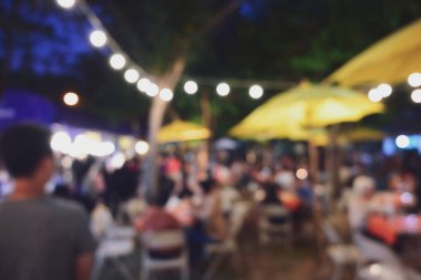 İnsanlar gece parti festivalinde ampul asılmış bahçe festivalinde kalabalıklar.