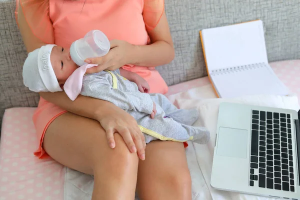 Mujer de negocios amamantando leche a su bebé y trabajando con computadora portátil —  Fotos de Stock