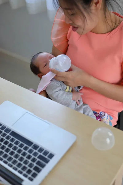 Empresária amamentando leite seu bebê e trabalhando com computador portátil — Fotografia de Stock