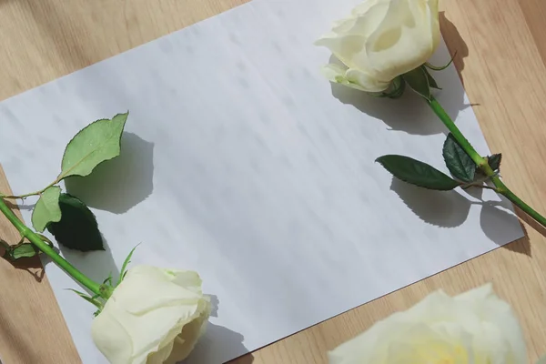 Empty blank paper letter note and white rose on wood table with window light in the morning day — Stock Photo, Image