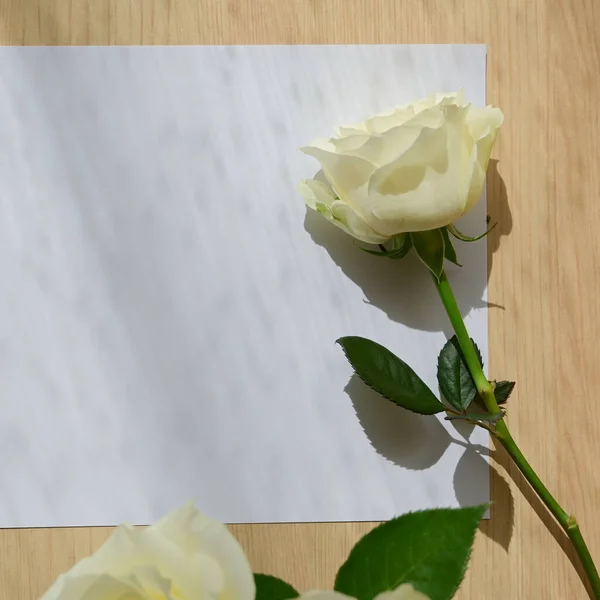 Κενό χαρτί σημείωμα γράμμα και λευκό τριαντάφυλλο στο τραπέζι από ξύλο με το φως του παραθύρου την ημέρα το πρωί — Φωτογραφία Αρχείου