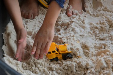 Çocuk kum parkında inşaat oyuncağı oynuyor.