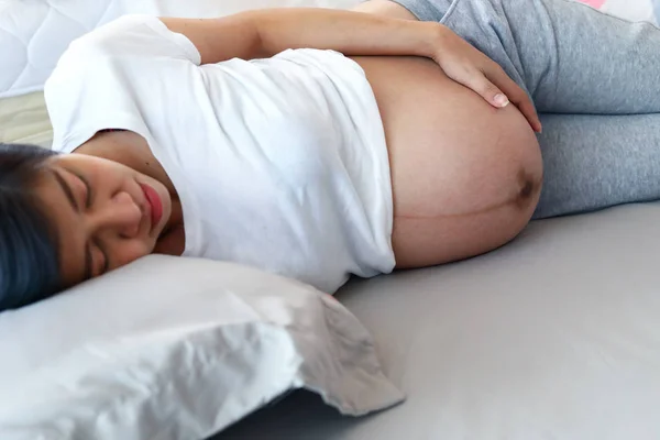 Moeder zwanger moederschap slapen op bed — Stockfoto