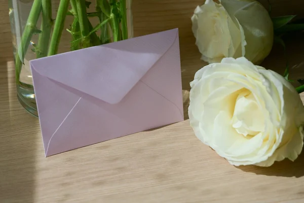 Pink envelope letter and white rose flower on wood table with sunlight in the morning — Stock Photo, Image