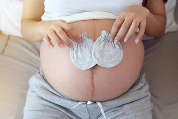 Schattig klein handschoen op moeder buik zwanger wachten voor baby pasgeboren — Stockfoto