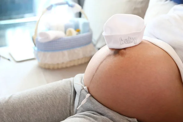 Bonitinho chapéu de bebê colocar em mãe barriga grávida à espera de recém-nascido — Fotografia de Stock