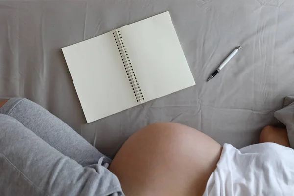 Página de papel em branco do livro de notas com a mãe grávida maternidade wriite memórias felizes para um bebê — Fotografia de Stock