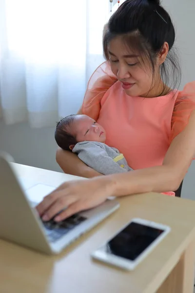 Mãe parentalidade um bebê recém-nascido dormindo em casa escritório, empresária digitando teclado laptop computador — Fotografia de Stock