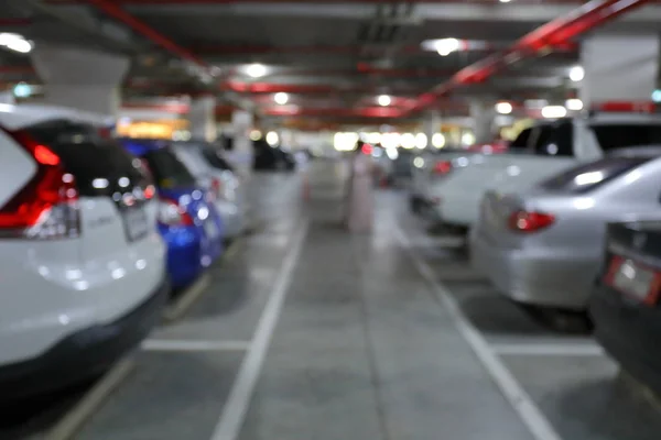 Subterrâneo do parque de estacionamento no edifício de negócios, imagem de fundo borrão — Fotografia de Stock