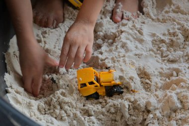 Çocuk kum parkında inşaat oyuncağı oynuyor.