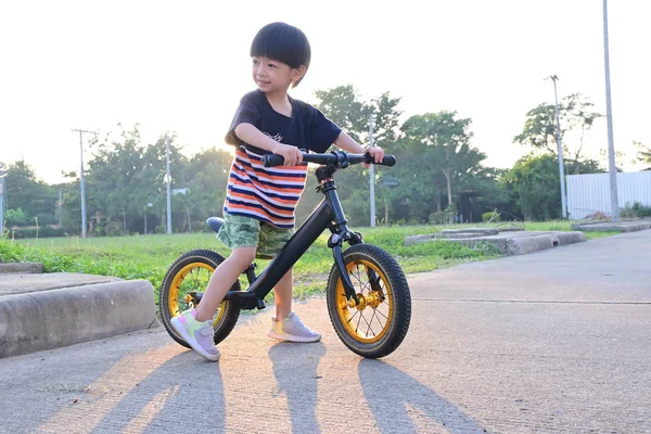 Cute boy playing balance bike in the park with sun light in the morning day — 스톡 사진