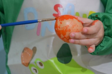 Mutlu çocuk tatlı paskalya yumurtası el sanatlarında suluboya resim yapıyor.