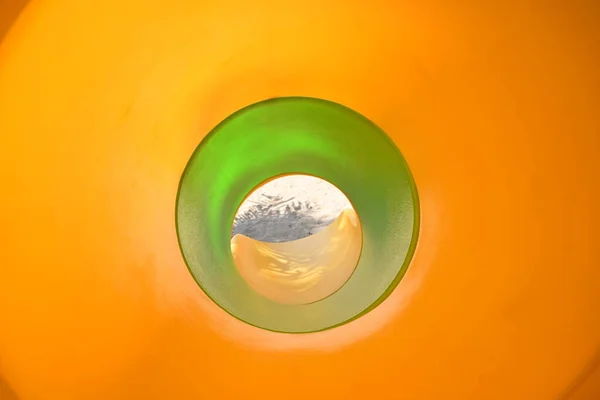 Green and yellow in tunnel tube of slide in sand playground — 스톡 사진