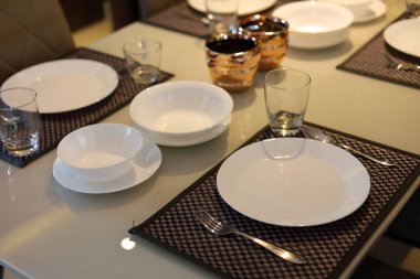 Beyaz tabak takımları yemek masasının üzerinde modern ev içi yemek odasının içinde.
