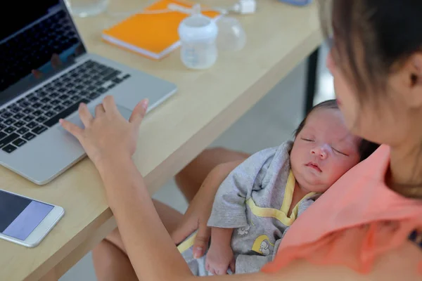 Mãe parentalidade um bebê recém-nascido dormindo em casa escritório, mulher de negócios digitando teclado laptop computador — Fotografia de Stock