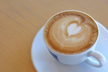 Kafe restoranındaki ahşap masaya konmuş sıcak latte içeceği, sabah kahvaltısı.