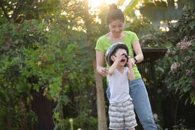 Anne oğluna yardım ediyor. Yaz sabahı bisiklet oynamak için kask takıyor.