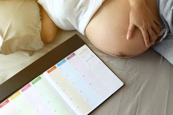 Mãe grávida maternidade mão abraço barriga com amor um bebê, mãe escrever agenda planejador nota memórias felizes — Fotografia de Stock