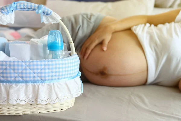 Mãe nova maternidade preparando fralda e garrafa de leite na cesta — Fotografia de Stock