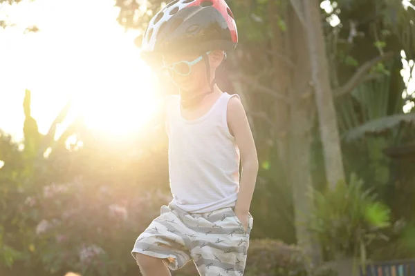 Счастливый ребенок носить солнцезащитные очки и спортивный шлем играть велосипедные упражнения летом утром — стоковое фото