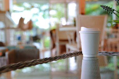 Kahve dükkanındaki cam masaya konan sıcak kahve bardağını kaldır.