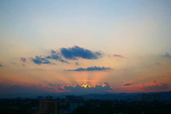 light rays of sun in sunset sky above the city