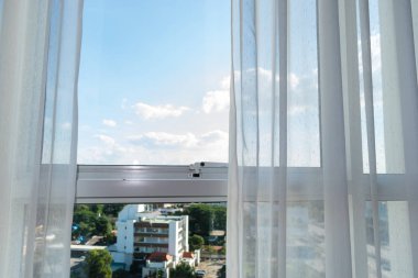 Beyaz perde cam pencerenin üzerinde, şehir manzaralı oda