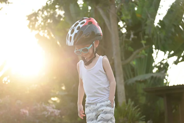 happy child wear sunglasses and sport helmet playing bicycle exercise in summer morning