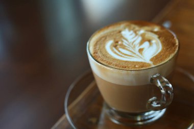 Kafe restoranındaki ahşap masaya konmuş sıcak latte.