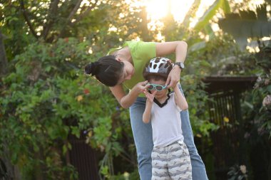 Anne oğluna yardım ediyor. Yaz sabahı bisiklet oynamak için kask takıyor.