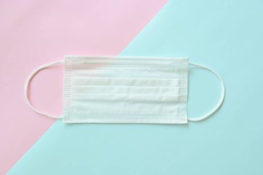 Pembe ve mavi pastel arka planda tıbbi yüz maskesi.