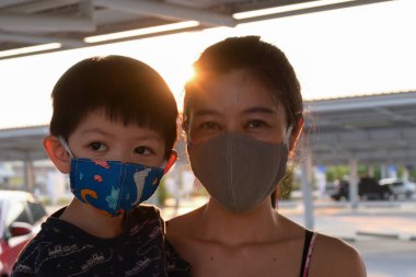 Asyalı sevimli çocuk ve kadın anne açık havada sabahleyin maske takıyor kendinizi hava kirliliği ve salgın hastalıklardan koruyun.