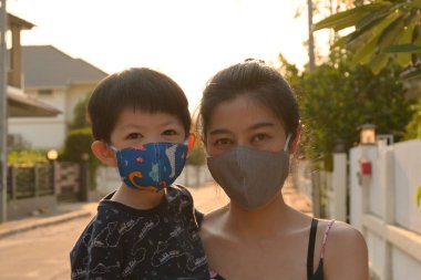 Asyalı sevimli çocuk ve kadın anne açık havada sabahleyin maske takıyor kendinizi hava kirliliği ve salgın hastalıklardan koruyun.