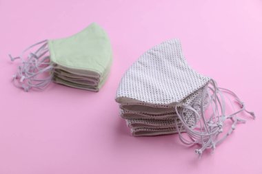 Beyaz ve yeşil yüz maskesi tasarımı. Moda kumaşından el yapımı. Pembe arka planda pamuk kumaş.